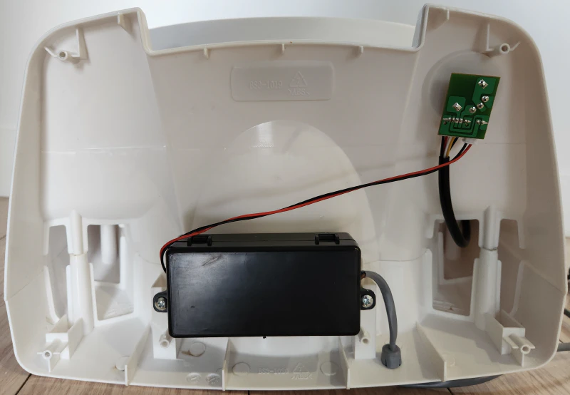Exposed base of the fan, showing a cable going into a black box. Another cable comes out of the black box, connecting to a very small circuit board which then has another cable connected which disappears into the fan case.